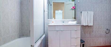 Un baño con una bañera, un lavabo con espejo y un inodoro.