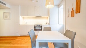 Una cocina moderna con armarios blancos, horno empotrado y una lámpara colgante.