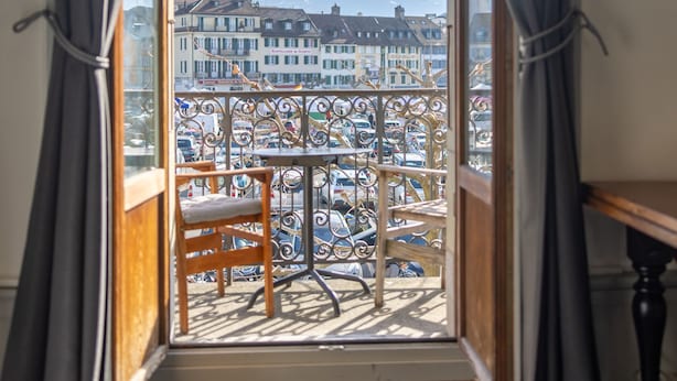 A room with a view of a cityscape through a window with curtains.