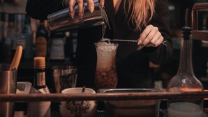 A bartender pouring a drink into a glass.