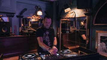 Ein DJ-Pult mit Plattenspieler und Mischpult, umgeben von Lautsprechern und einem Spiegel.