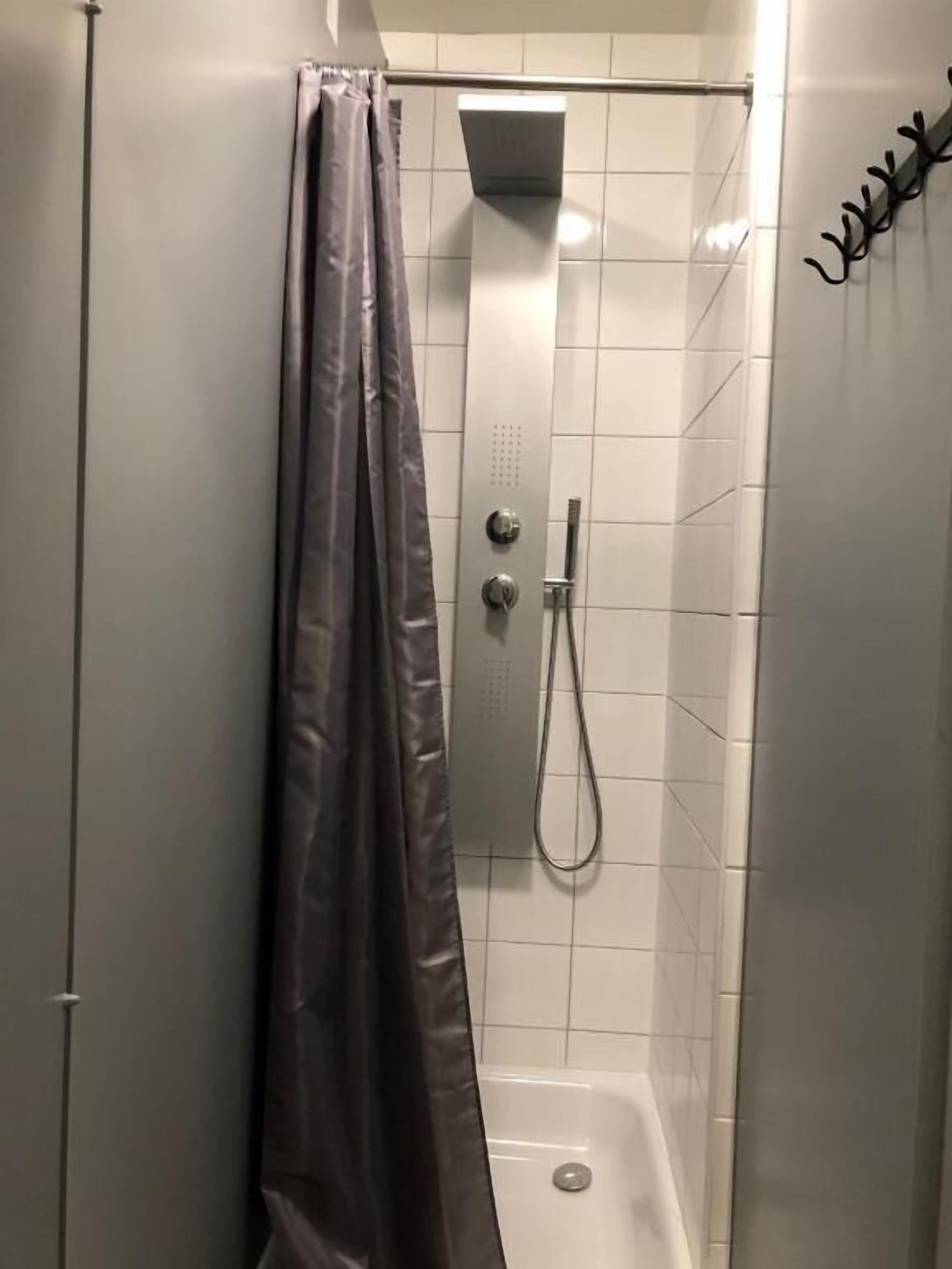 A shower area with a showerhead, control knobs, and a curtain.