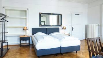 Un dormitorio ordenado con una cama doble, mesitas de noche con lámparas, un espejo y un radiador.