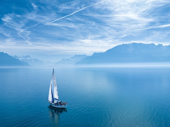 Un velero en aguas tranquilas con montañas al fondo.