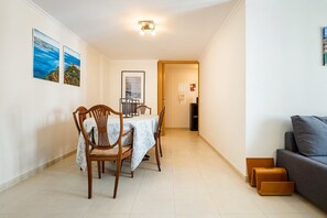 Cozy living area with a dining table for four, sofa, and wooden chairs.