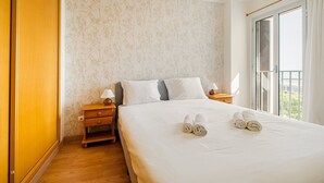Una habitación de hotel con una cama grande, dos mesitas de noche y una ventana con cortinas.