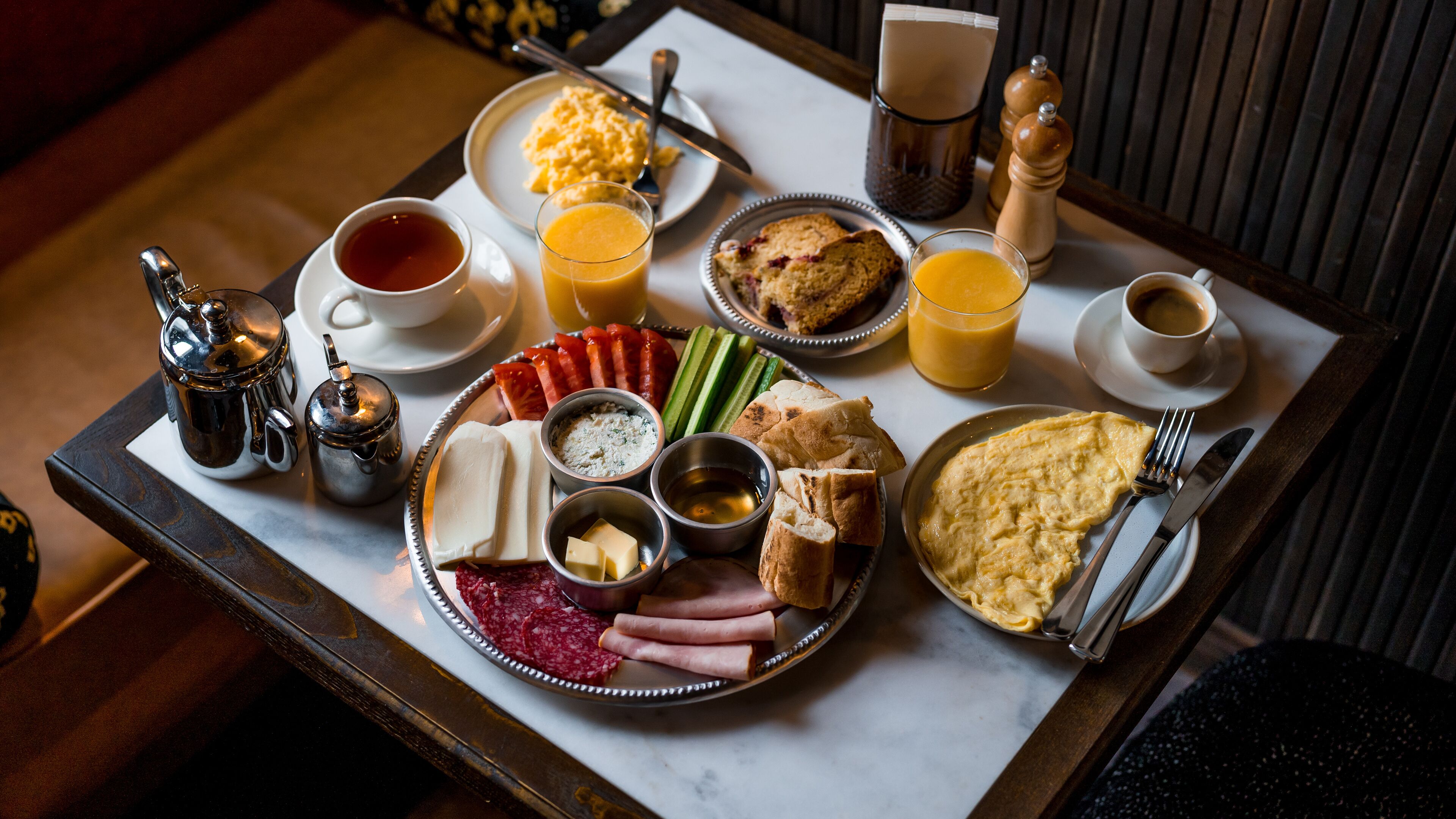 A breakfast tray with eggs, ham, cheese, bread, and beverages.