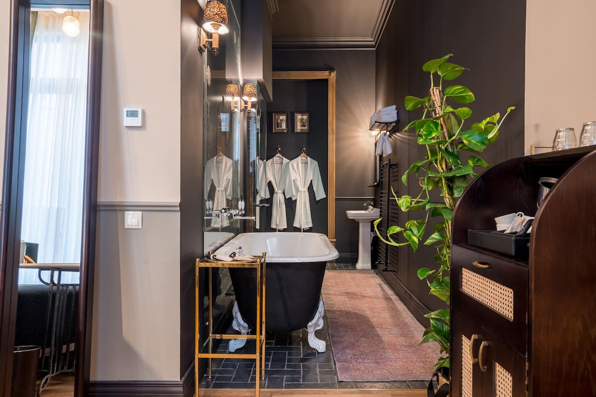 A modern bathroom with a freestanding bathtub, a large mirror, and a potted plant.
