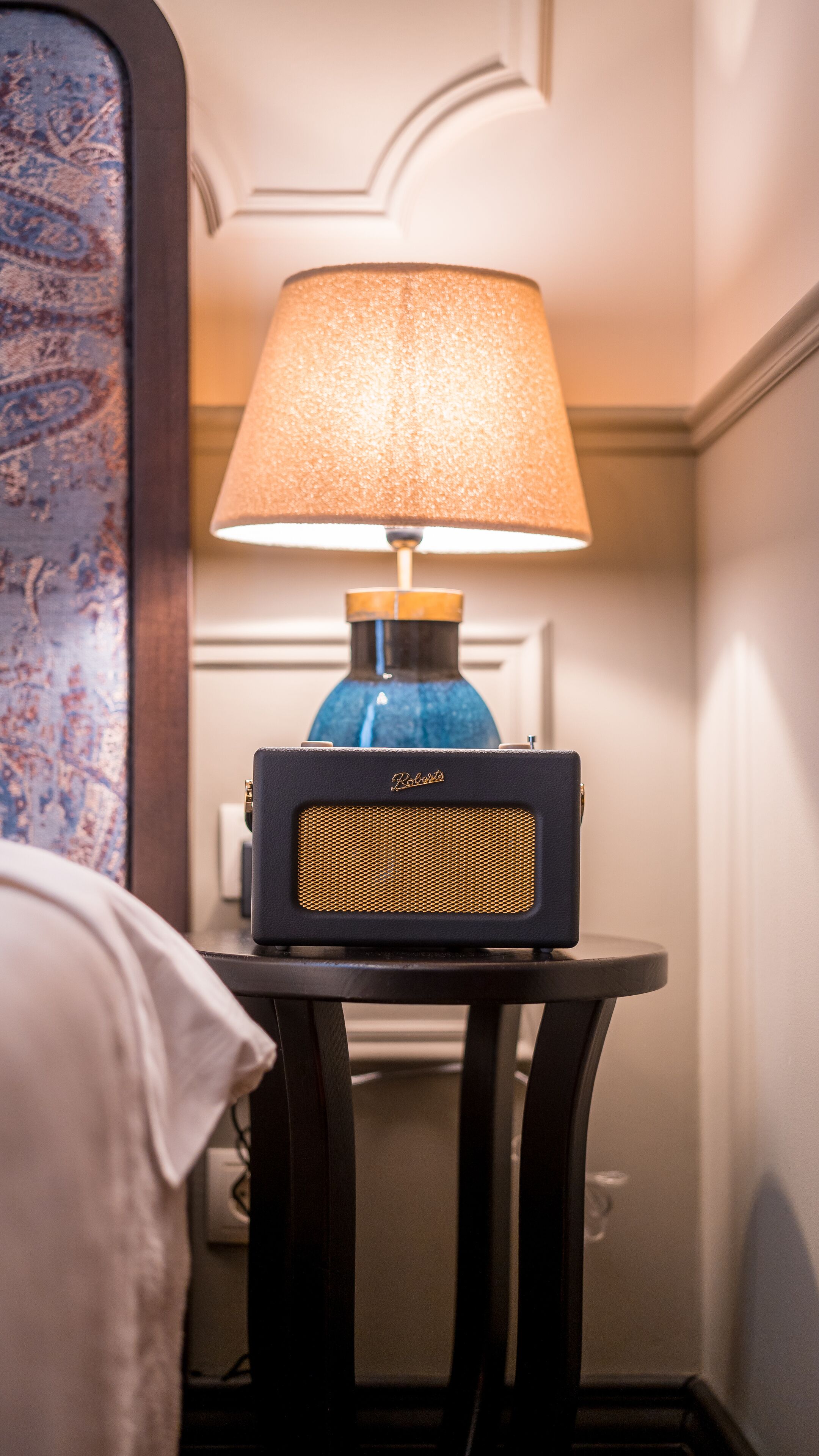 A lamp with a blue base and a beige lampshade on a small table.