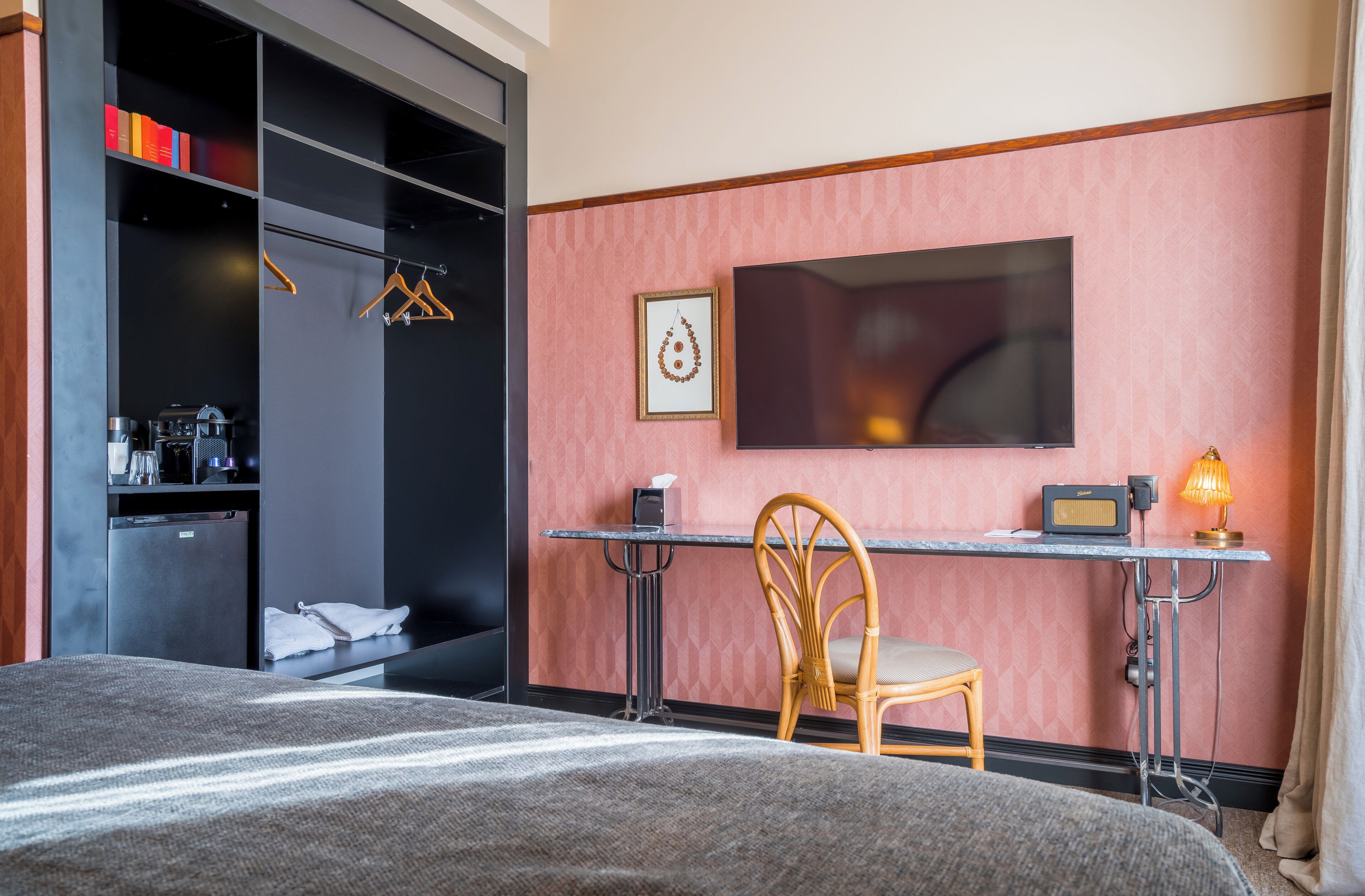 Une chambre d’hôtel comprenant un lit, un bureau avec une chaise, une télévision et une armoire.