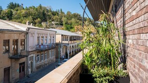 A narrow street with historic buildings, a balcony with plants, and a clear blue sky. - Communal Hotel Kutaisi (Kutaisi)