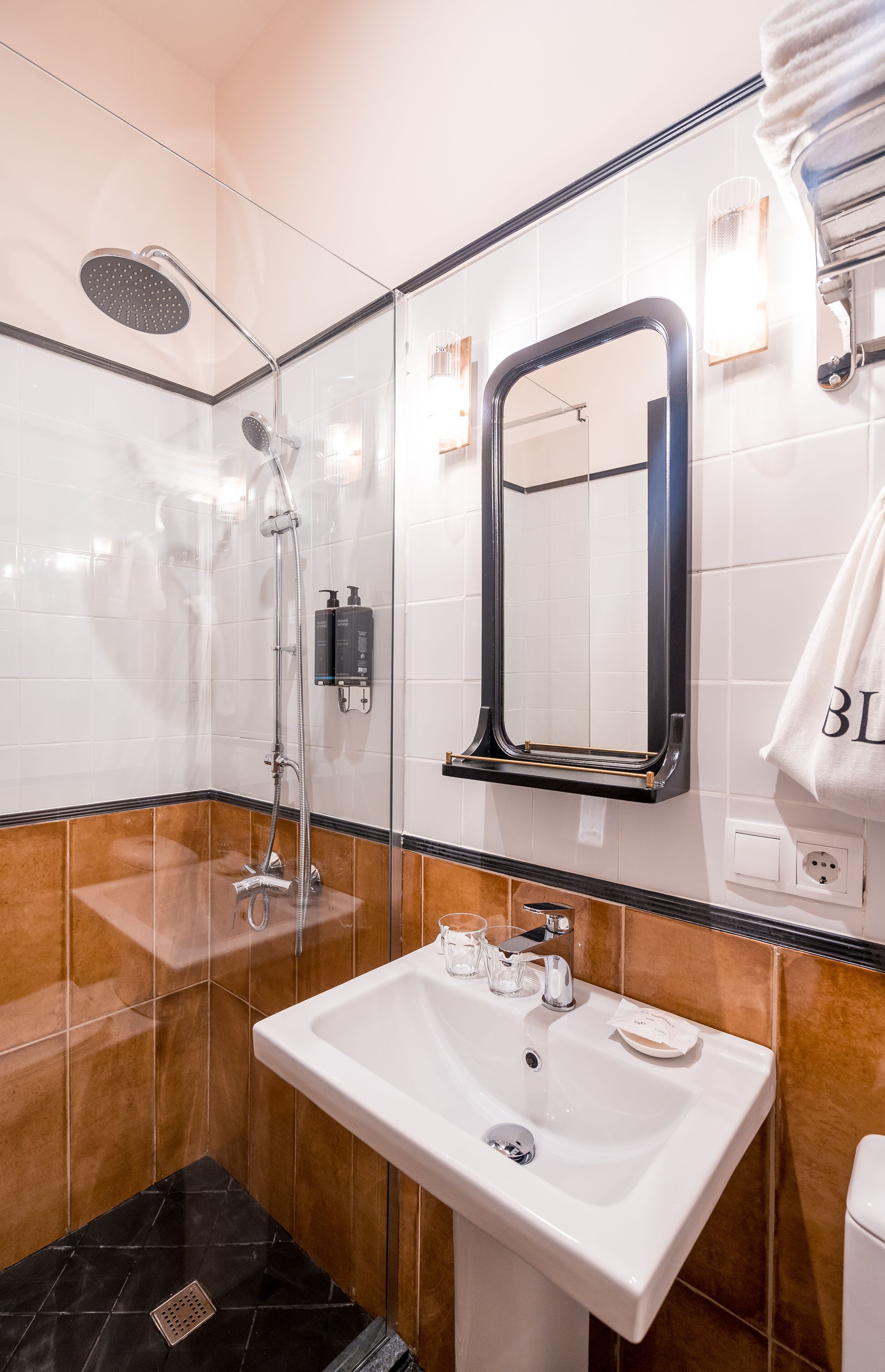 Une salle de bain moderne avec une douche à parois de verre, un grand miroir, un lavabo blanc et un porte-serviettes.