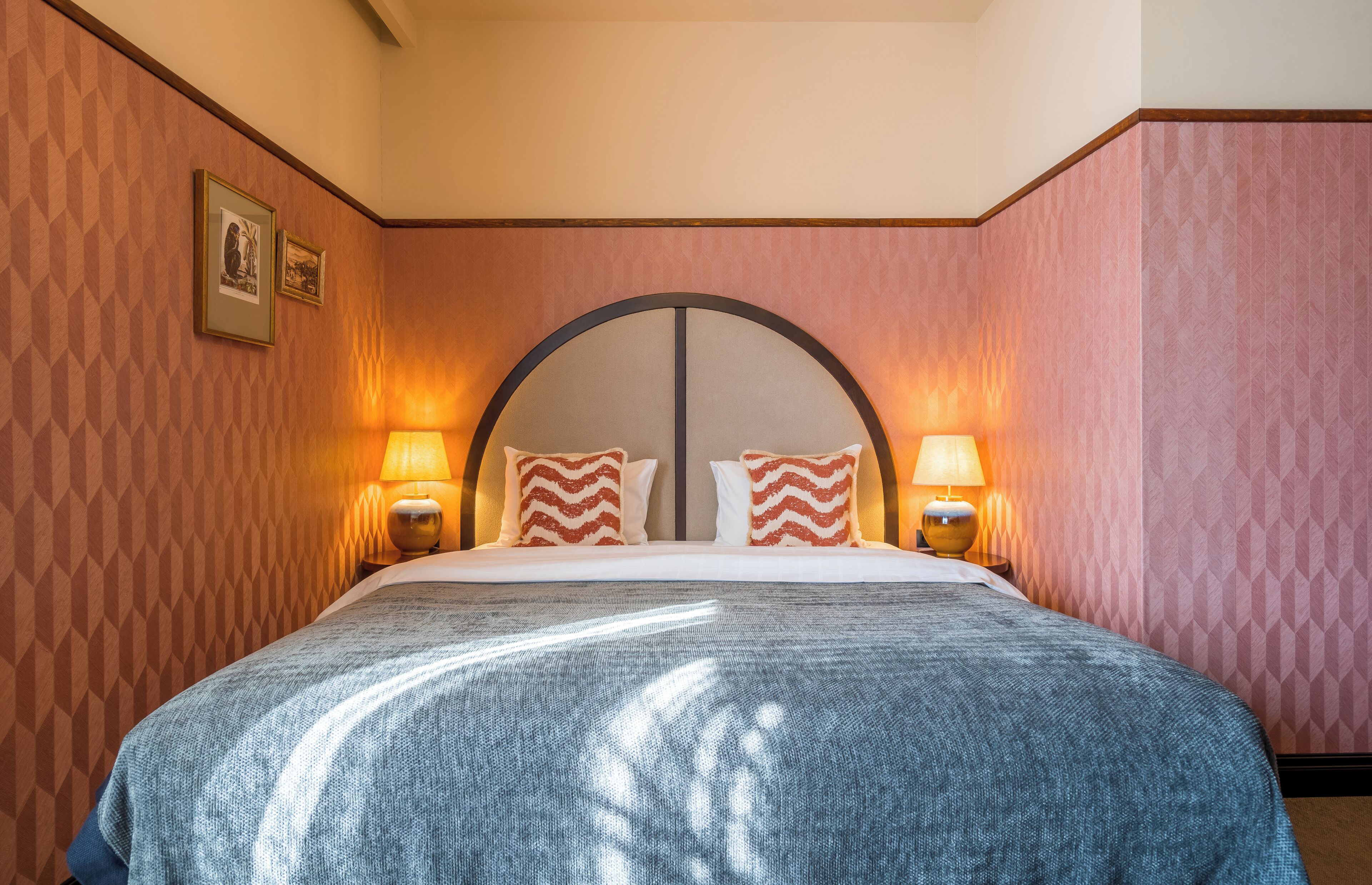 Ein Hotelzimmer mit einem großen Bett, zwei Nachttischlampen und einer Wand mit Muster.