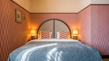 Ein Hotelzimmer mit einem großen Bett, zwei Nachttischlampen und einer Wand mit Muster.