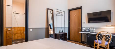A hotel room with a large bed, a desk with a chair, a television, and a mirror.