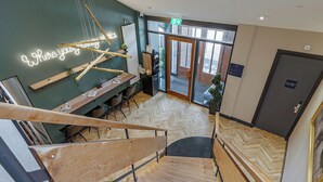 A modern hotel interior with a staircase, wooden flooring, a neon sign, and a view of the outside. - Bens The Walton (Amsterdam)