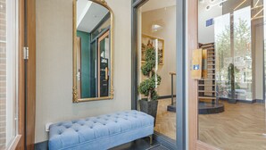 A reception area with a bench, a large mirror, and a potted plant. - Bens The Walton (Amsterdam)