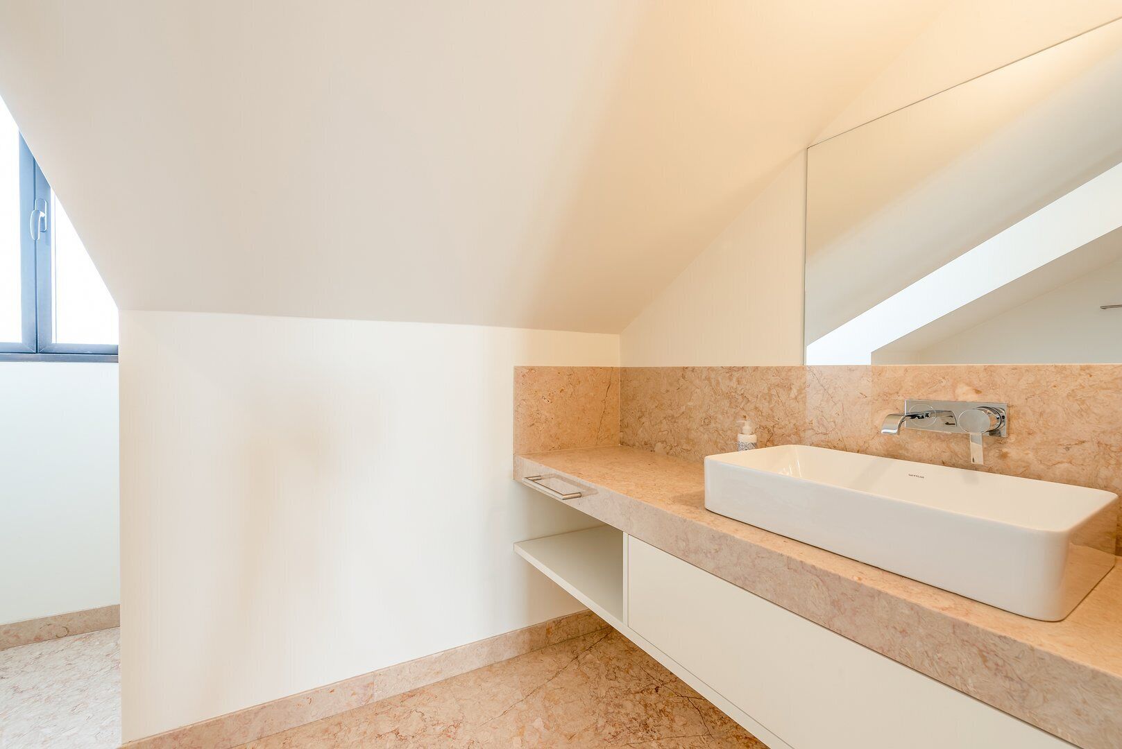 A modern bathroom with a white sink, marble countertop, and a large mirror.