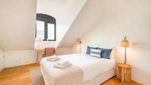 A bedroom with a large bed, two bedside lamps, a desk, and a chair. - GuestReady - Conde das Acáçovas 3 (Paço de Arcos)