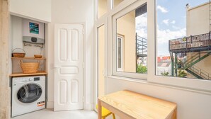 A compact laundry room with a washing machine, a drying rack, and a small table.