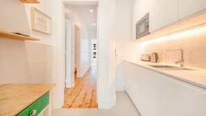 A modern kitchen with white cabinetry, a wooden countertop, and a built-in oven.