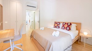 Ein Hotelzimmer mit Bett, Nachttisch, Stuhl, Schreibtisch und Klimaanlage.