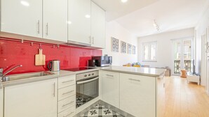 Eine moderne Küche mit weißen Schränken, einer roten Spritzschutzwand und einem gefliesten Boden.