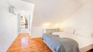 Een slaapkamer met een bed, bedlampjes en een houten vloer.
