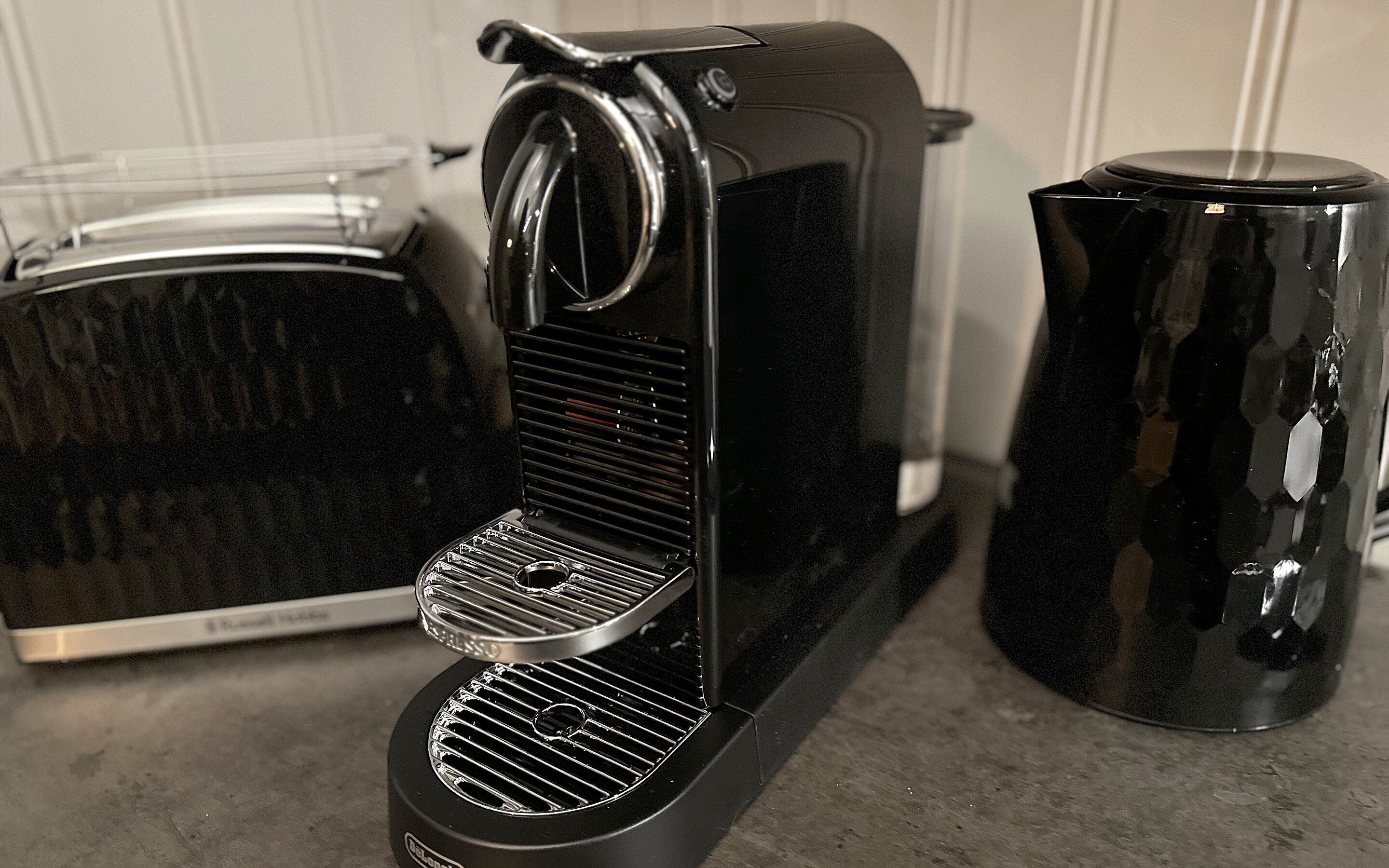 Une machine à café avec un bac de récupération, un grille-pain et une cafetière, le tout posé sur un plan de travail.