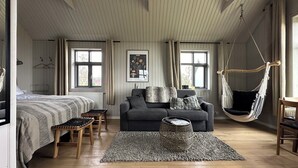 A cozy room with a bed, a sofa, a hanging chair, and a rug.