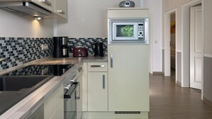 A compact kitchen with a microwave, kettle, and coffee maker on the counter. - Amselresidenz 1 - AMSEL (Binz)