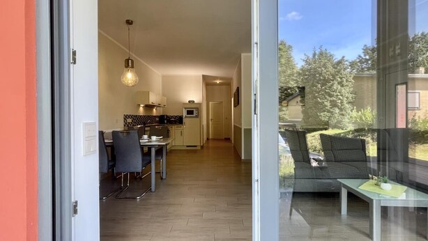A modern kitchen with a dining area, a glass door leading to a balcony with a sofa and table. - Amselresidenz 1 - AMSEL (Binz)
