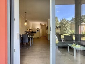 Un appartement moderne comprenant un coin repas, une cuisine et un balcon aménagé avec des sièges.