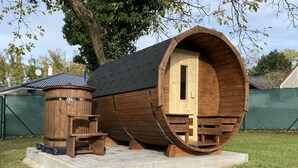 A wooden barrel-shaped structure with a door, a small wooden bench, and a cylindrical object with a ladder. - Residence Dymokury (Stredoceský kraj)