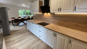 A modern kitchen with white cabinets, a wooden countertop, and a built-in stove. - Residence Dymokury (Stredoceský kraj)