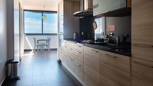 Eine moderne Küche mit Holzschränken, einer schwarzen Arbeitsplatte und Blick zum Himmel durch ein großes Fenster.