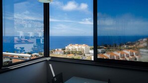 Ein Zimmer mit einem großen Fenster und Blick auf das Meer und die Bebauung.
