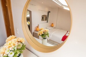 A hotel room with a bed, bedside lamps, a mirror, and a vase of flowers.