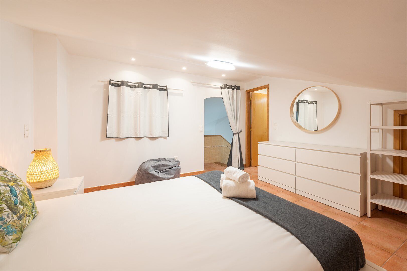 Un dormitorio con cama, mesitas de noche, lámpara, armario y espejo.