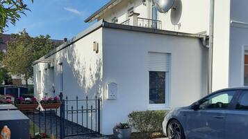 En modern vit byggnad med satellitantenner, en bil parkerad framför och en asfalterad uppfart.