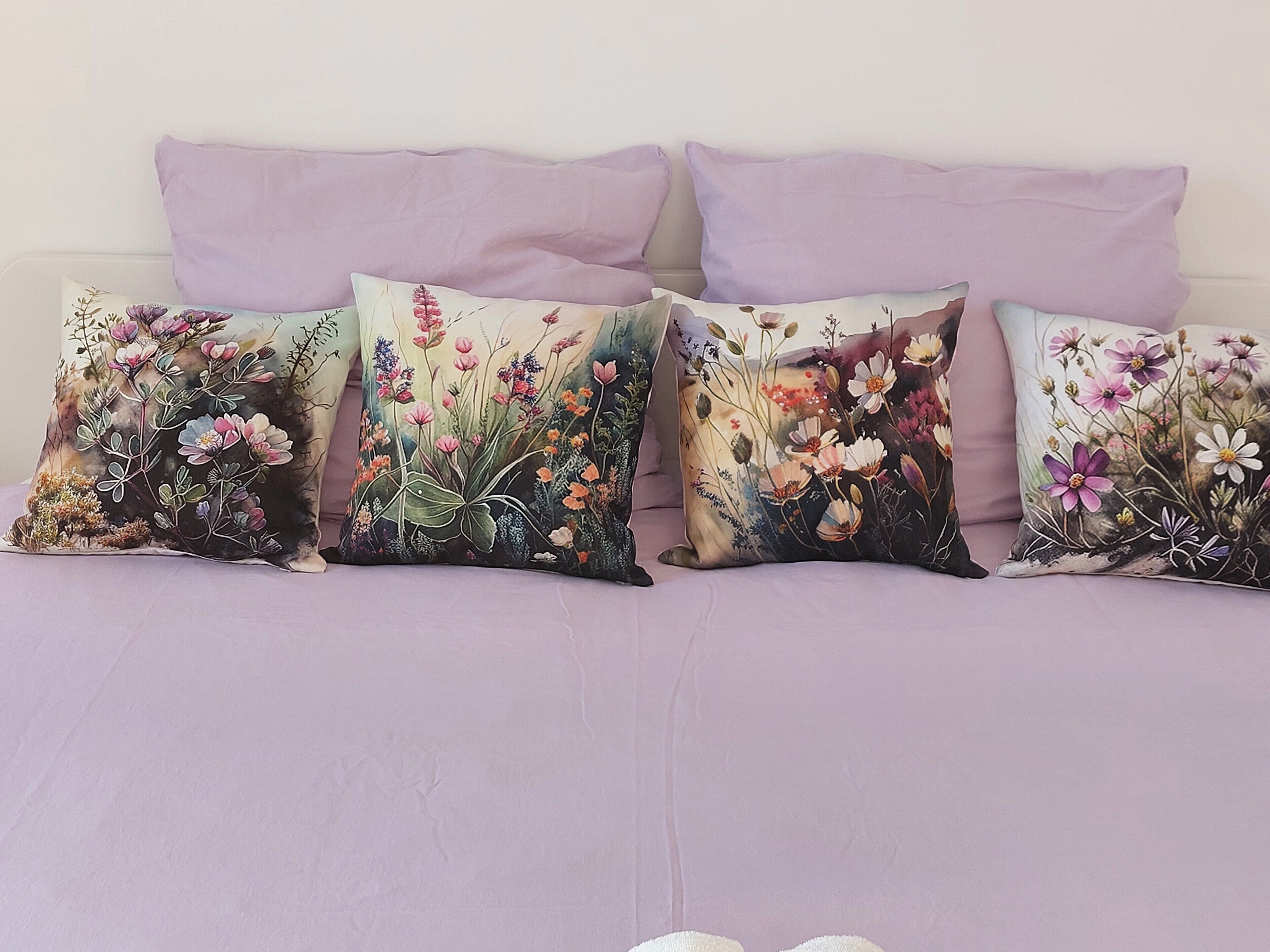 Ein Bett mit vier dekorativen Kissen mit floralen Mustern.