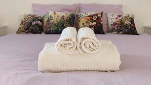A neatly made bed with rolled towels, a floral pillow, and a painting of trees on the wall. - Moderne WHG in Churfranken: Fahrrad-wandertouren & Geschäftlich/monteuer😊 (Elsenfeld)