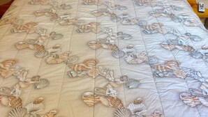 A bed with a beige quilt featuring a seashell pattern, a wooden headboard, and a bedside table with a lamp. - Cute, Quiet And Meticulously Kept. This Private Studio Is Close To Everything.
 (Brandon)
