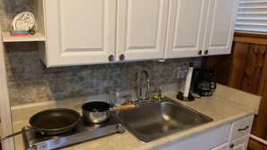 A kitchen with white cabinets, a granite countertop, a stainless steel sink, a coffee maker, and a frying pan. - Cute, Quiet And Meticulously Kept. This Private Studio Is Close To Everything.
 (Brandon)