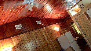 A room with wooden walls and ceiling, a ceiling fan, a vent, and a refrigerator. - Cute, Quiet And Meticulously Kept. This Private Studio Is Close To Everything.
 (Brandon)