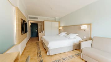 A hotel room with a bed, a bedside table, a lamp, a sofa, and a television.