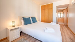 Ein modernes Schlafzimmer mit einem großen Bett, einem Holzschrank und einem Nachttisch mit Lampe.