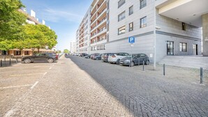 Ein Parkplatz mit mehreren Autos, ein Gebäude mit Balkonen und einem klaren Himmel.