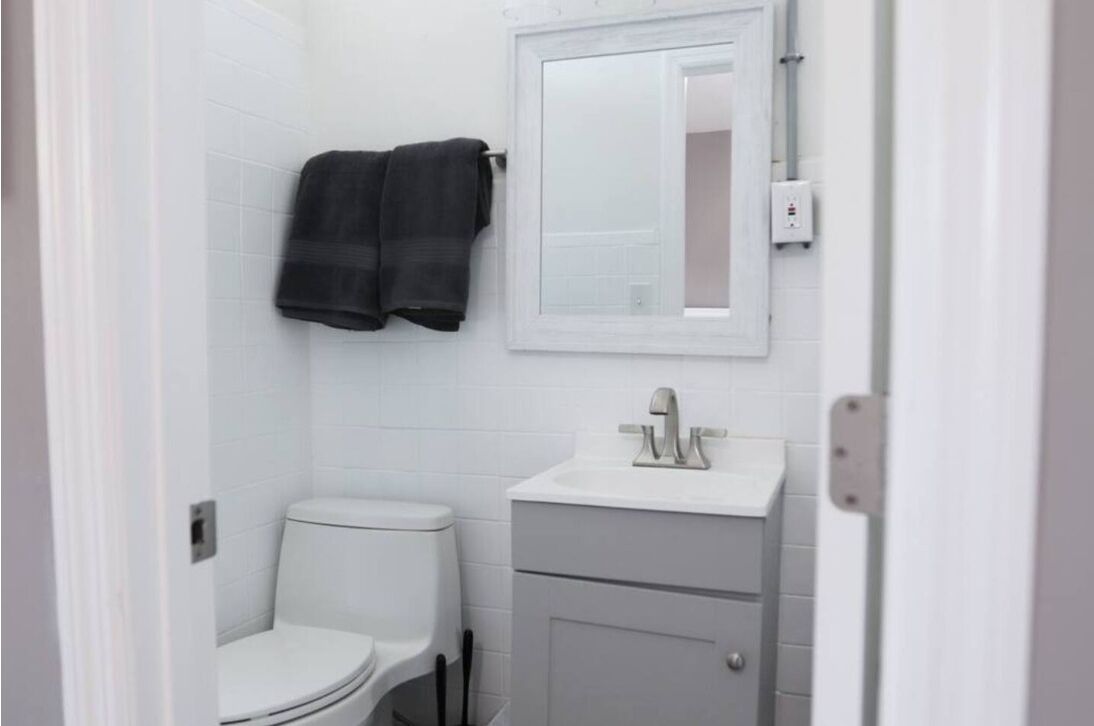 A bathroom with a toilet, a sink, and a mirror.