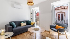 Un salon moderne avec un canapé gris, une table basse ronde et un balcon doté d’une balustrade.